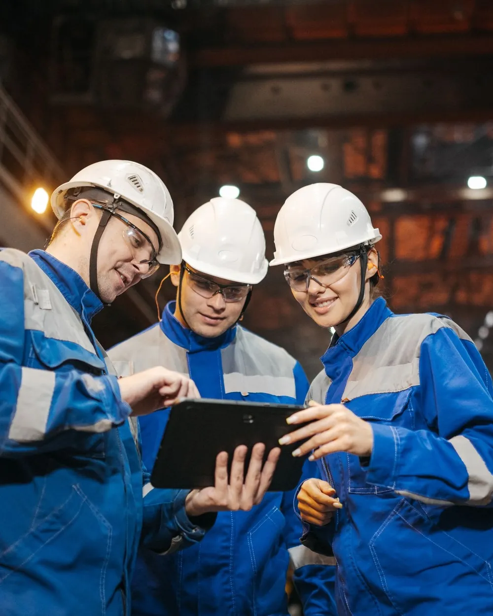 Equipe de engenheiros conferindo dados de ativos em um tablet dentro de uma planta industrial