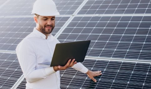young-architect-standing-by-solar-panels-making-diagnostics-on-computer
